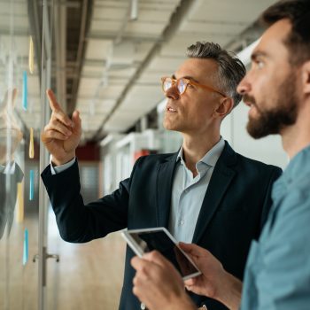 scrum-master-usando-notas-adhesivas-de-pie-cerca-de-la-placa-de-planificacion-en-la-oficina